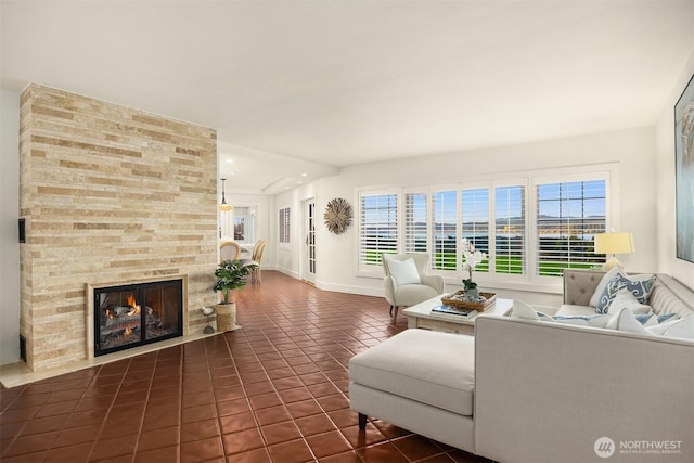 living area with baseboards, a large fireplace, a healthy amount of sunlight, and dark tile patterned floors