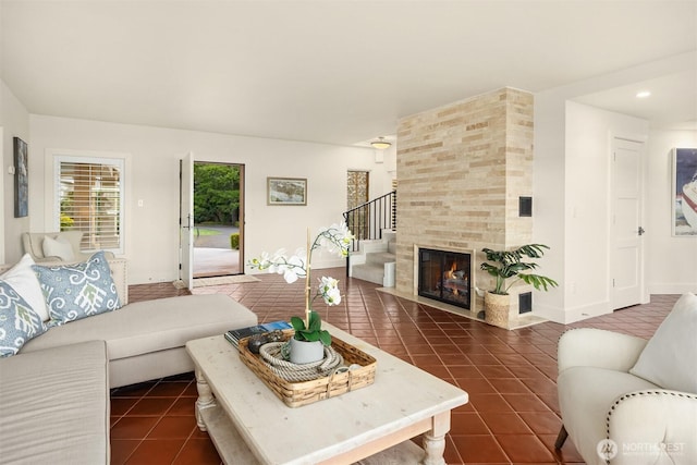 living area featuring stairway, baseboards, dark tile patterned flooring, and a fireplace