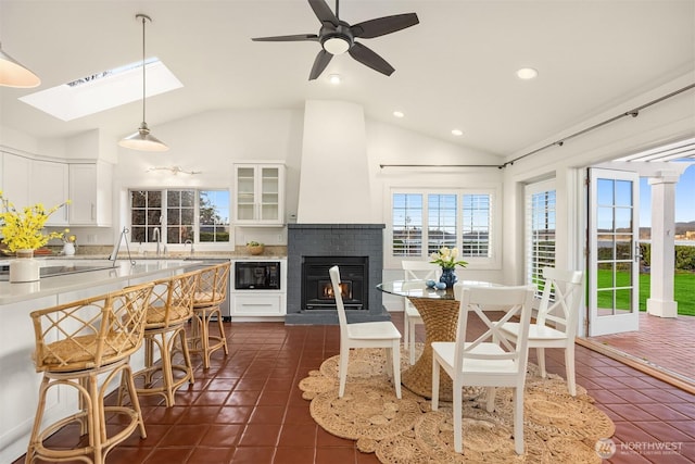 dining space with a skylight, dark tile patterned floors, and a healthy amount of sunlight