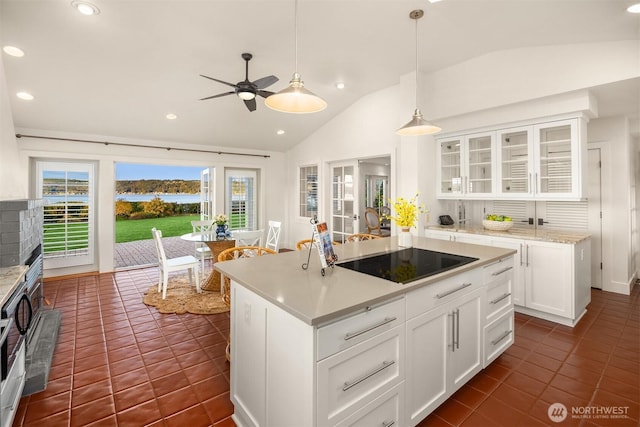 kitchen with lofted ceiling, light countertops, white cabinets, black electric stovetop, and dark tile patterned floors