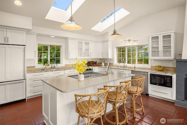 kitchen featuring dark tile patterned flooring, a kitchen island, white cabinets, black microwave, and dishwasher