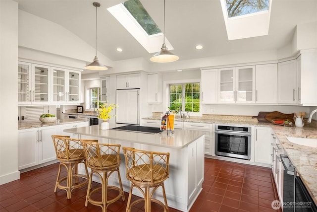 kitchen featuring a kitchen island, oven, paneled built in refrigerator, black electric cooktop, and a sink