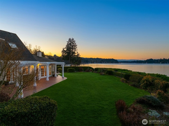 view of yard featuring a patio area, a pergola, and a water view