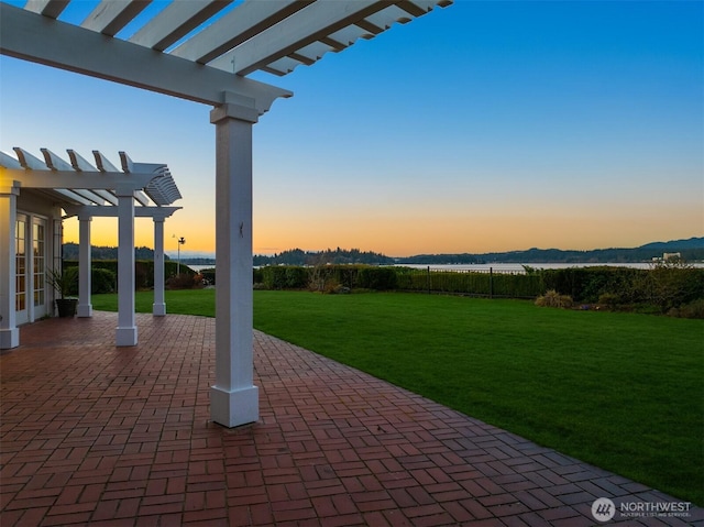 patio terrace at dusk featuring a yard and a pergola