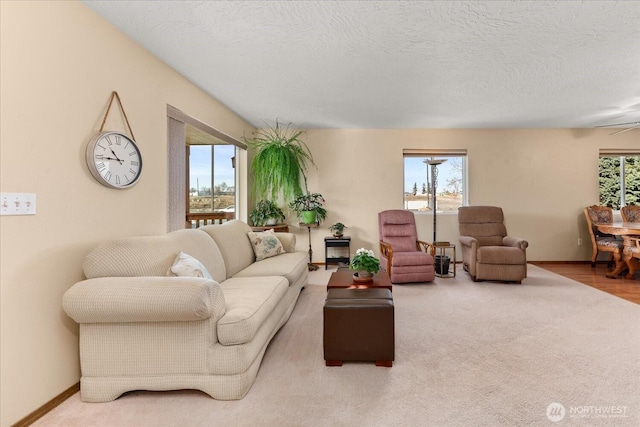 carpeted living room featuring a textured ceiling and baseboards