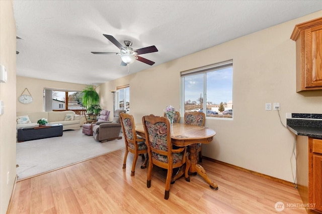 dining room with baseboards, light wood-type flooring, and a ceiling fan