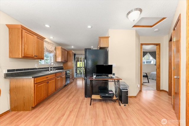 kitchen with dark countertops, recessed lighting, light wood-type flooring, and a sink