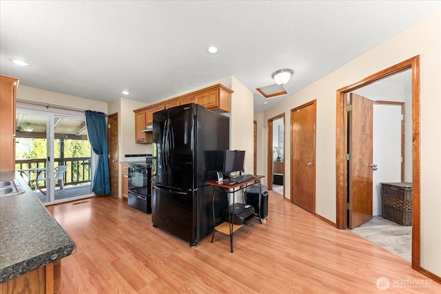 kitchen featuring dark countertops, light wood-type flooring, recessed lighting, brown cabinets, and black appliances