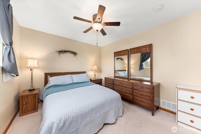 bedroom featuring ceiling fan, light colored carpet, visible vents, and baseboards