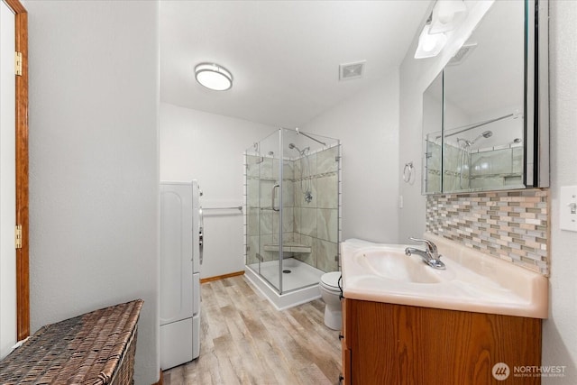 full bathroom featuring vanity, wood finished floors, visible vents, decorative backsplash, and a shower stall