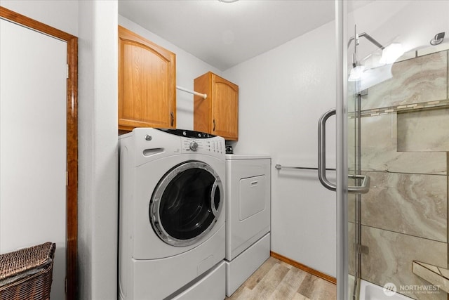 laundry room with cabinet space, light wood finished floors, and washing machine and clothes dryer