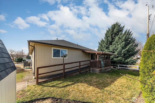 rear view of house featuring cooling unit, a yard, and fence