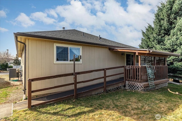 rear view of house with cooling unit, a lawn, roof with shingles, and a wooden deck