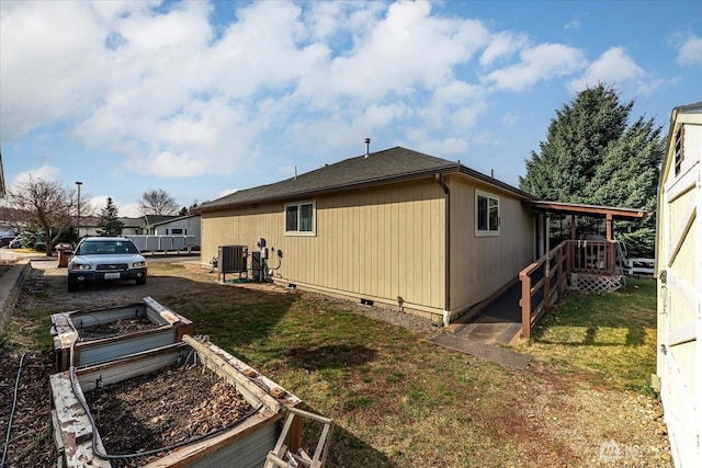 view of side of property with crawl space, central air condition unit, a yard, and a vegetable garden