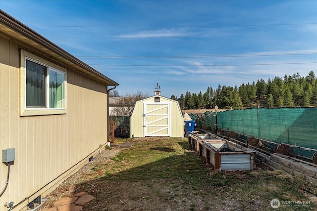 view of yard with a storage shed, a garden, a fenced backyard, and an outdoor structure