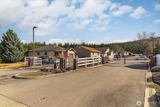 view of street with a gated entry, a residential view, curbs, and a gate