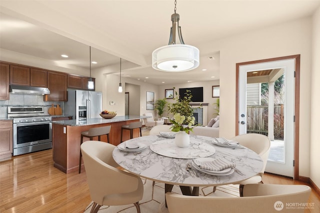 dining room featuring recessed lighting, a fireplace, and light wood-type flooring