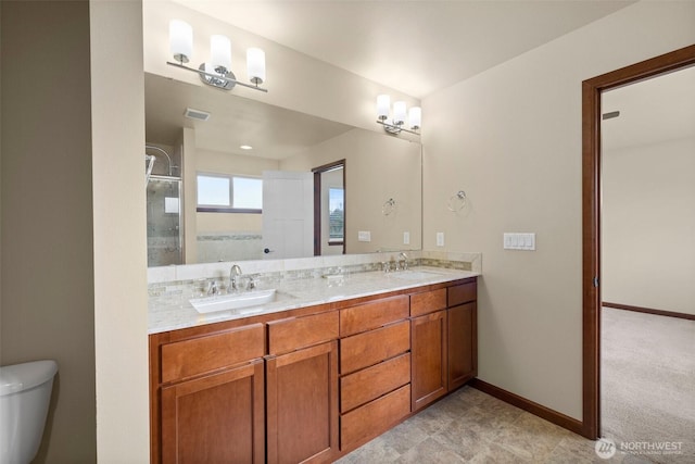 bathroom with double vanity, toilet, baseboards, and a sink