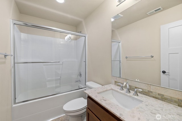 bathroom featuring shower / bath combination with glass door, visible vents, toilet, and vanity