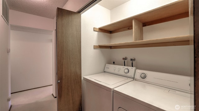 laundry area featuring visible vents, washing machine and dryer, light colored carpet, laundry area, and a textured ceiling