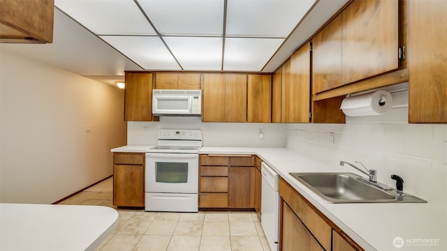 kitchen featuring white appliances, light countertops, and a sink