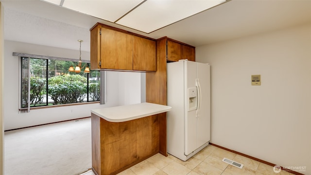 kitchen featuring visible vents, brown cabinets, white refrigerator with ice dispenser, a peninsula, and a chandelier