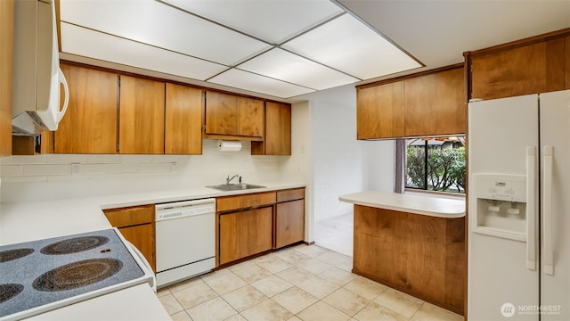 kitchen featuring a sink, white appliances, brown cabinets, and light countertops