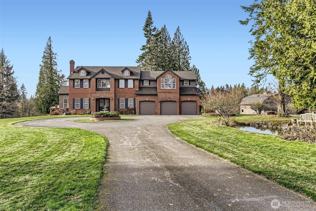 view of front of home with driveway, a front lawn, a chimney, and an attached garage