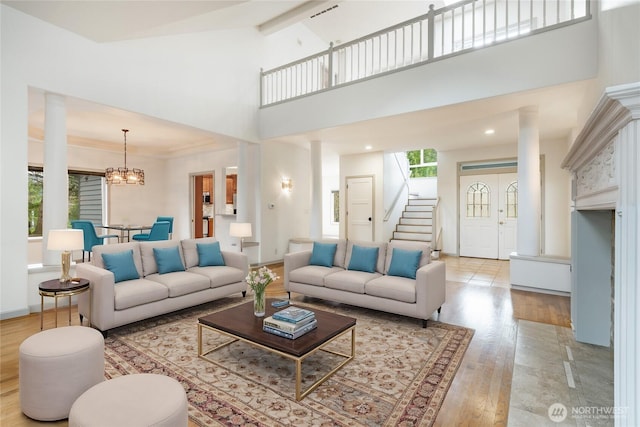 living area with a notable chandelier, stairway, light wood-type flooring, and baseboards