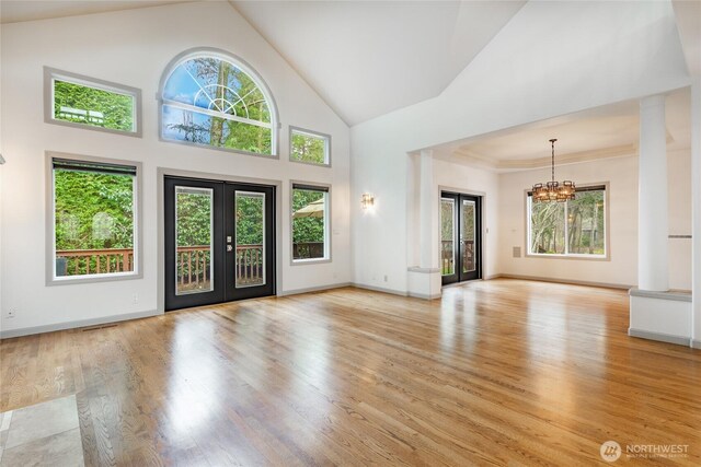 entrance foyer with light wood-type flooring, french doors, plenty of natural light, and an inviting chandelier