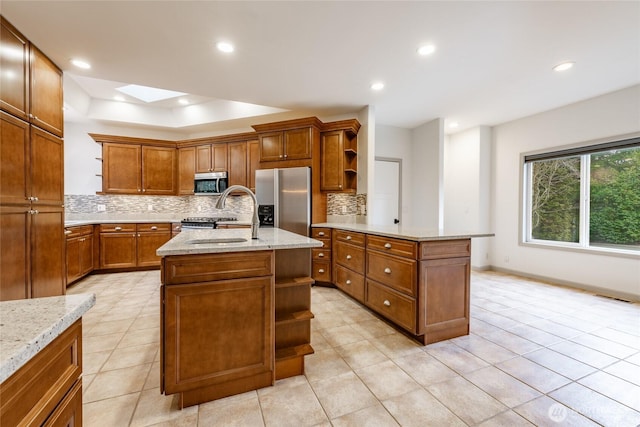 kitchen featuring brown cabinetry, open shelves, a skylight, a sink, and appliances with stainless steel finishes