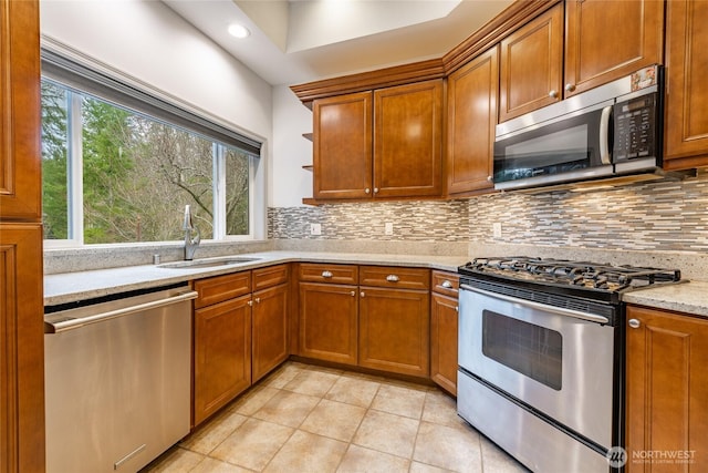 kitchen with a sink, stainless steel appliances, brown cabinets, and backsplash