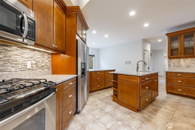 kitchen with brown cabinets, a sink, backsplash, recessed lighting, and appliances with stainless steel finishes