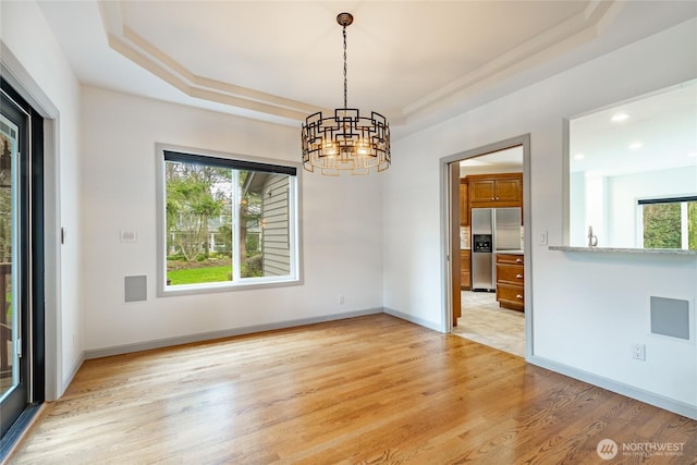 unfurnished room with baseboards, recessed lighting, a raised ceiling, light wood-type flooring, and a chandelier