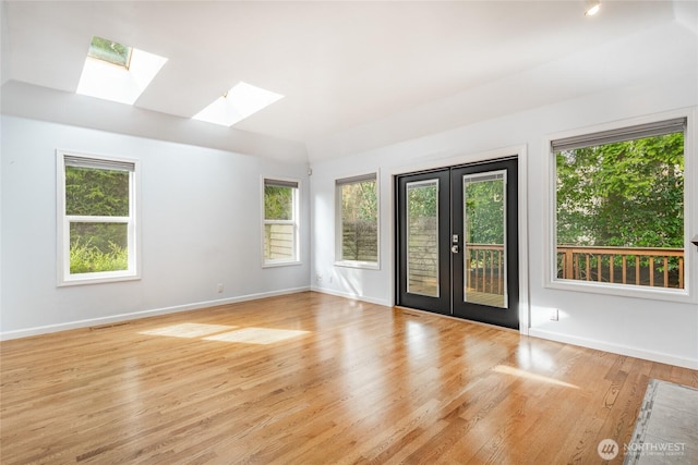 spare room with french doors, baseboards, and light wood-style flooring