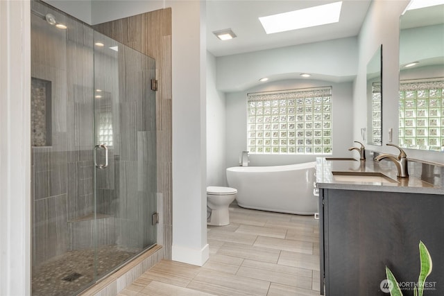 bathroom featuring a freestanding bath, double vanity, a stall shower, a skylight, and a sink
