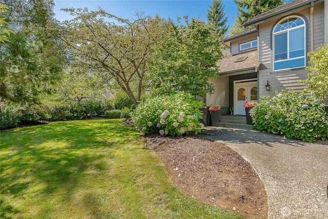 doorway to property with driveway and a yard