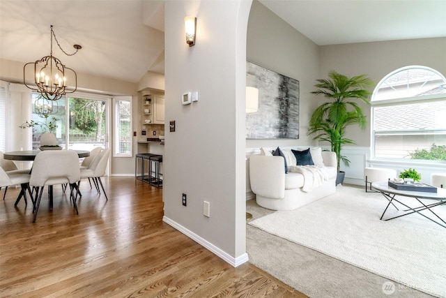 dining space featuring vaulted ceiling, baseboards, an inviting chandelier, and wood finished floors