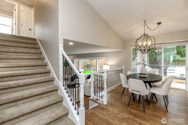 dining space featuring baseboards, stairway, an inviting chandelier, wood finished floors, and high vaulted ceiling