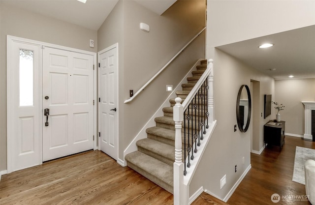 foyer with recessed lighting, a fireplace, baseboards, and wood finished floors