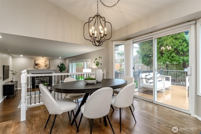 dining room featuring a glass covered fireplace, an inviting chandelier, wood finished floors, and baseboards