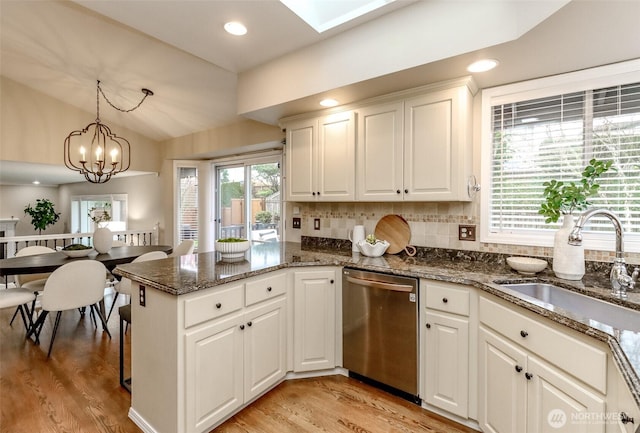 kitchen with light wood finished floors, dishwasher, lofted ceiling, and a sink