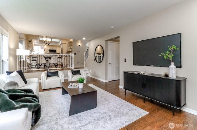 living room featuring a chandelier, baseboards, and wood finished floors