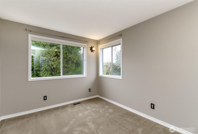 carpeted empty room featuring baseboards and visible vents