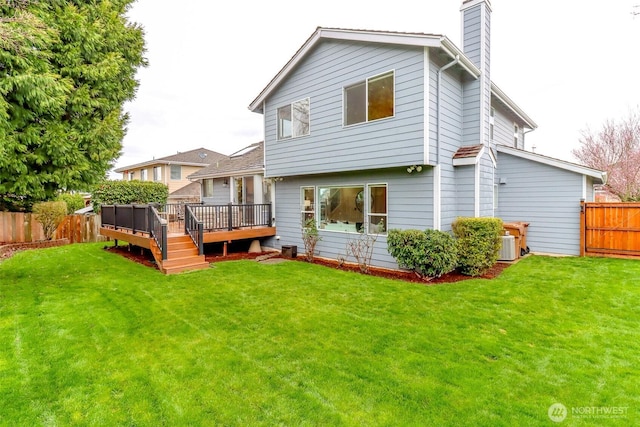 rear view of house featuring a deck, a lawn, a chimney, and a fenced backyard