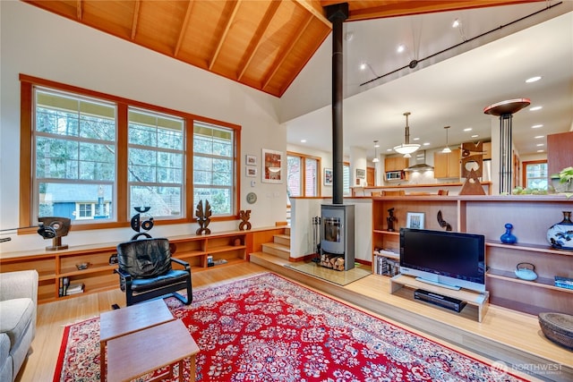 living area featuring stairs, wood ceiling, wood finished floors, and a wood stove