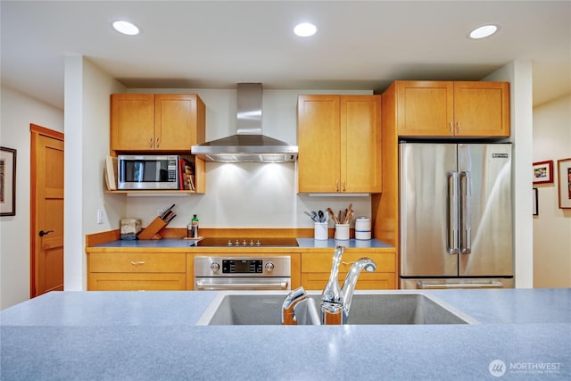 kitchen featuring recessed lighting, stainless steel appliances, wall chimney exhaust hood, and a sink