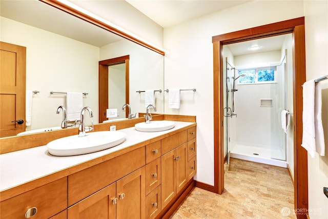 full bath featuring double vanity, a shower stall, baseboards, and a sink