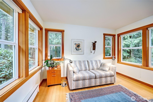 living room featuring baseboard heating, baseboards, and light wood-style floors