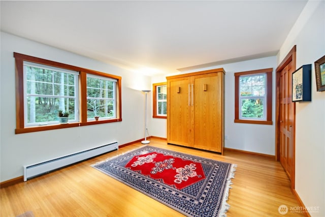 foyer entrance with a baseboard heating unit, baseboards, and light wood-style flooring